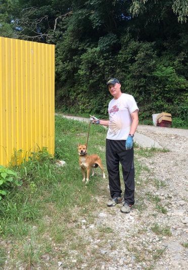 A man is standing next to a small dog on a leash.