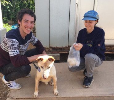 A man and a woman squatting next to a dog