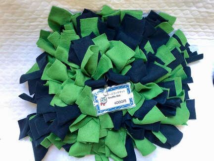 A green and black snuffle mat with a tag on it