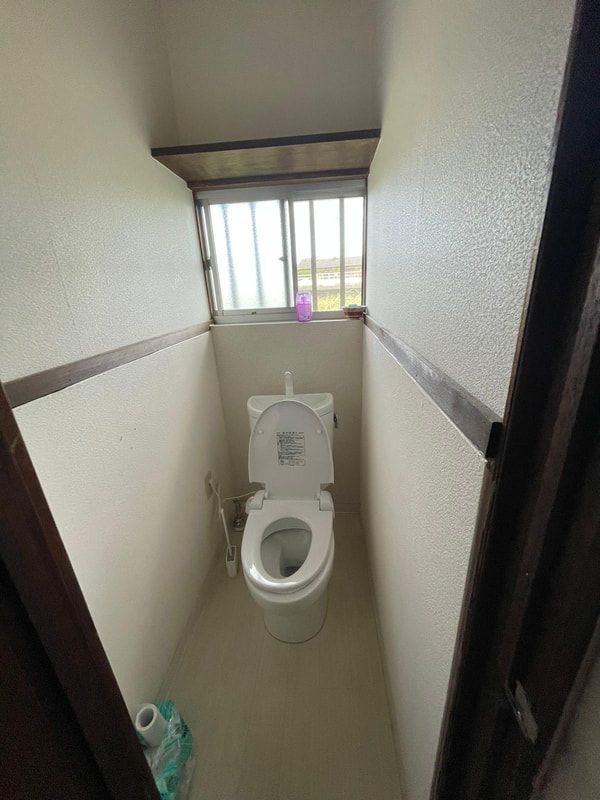 A small bathroom with a toilet and a window.