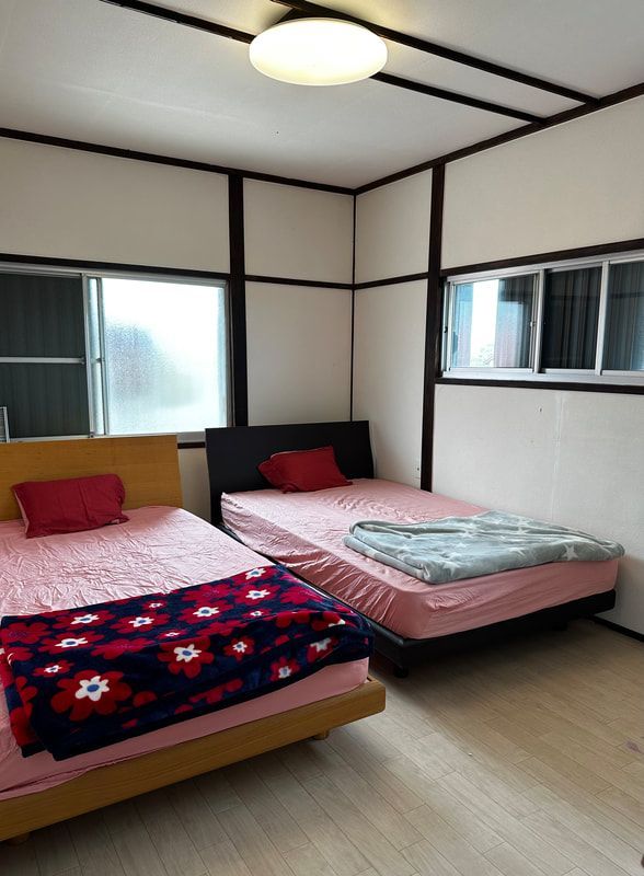 A bedroom with two beds and a window.