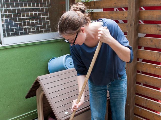 A woman wearing glasses is sweeping the floor with a broom.