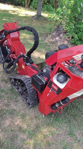 Red Ditch Witch trencher on a grassy lawn, ready for digging.
