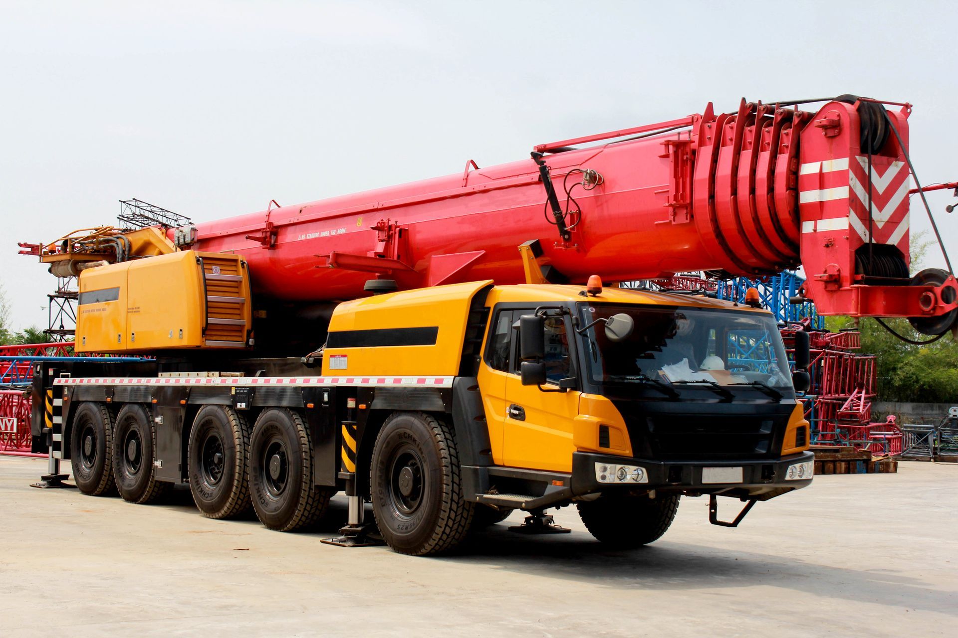 A yellow and red crane truck is parked in a parking lot.