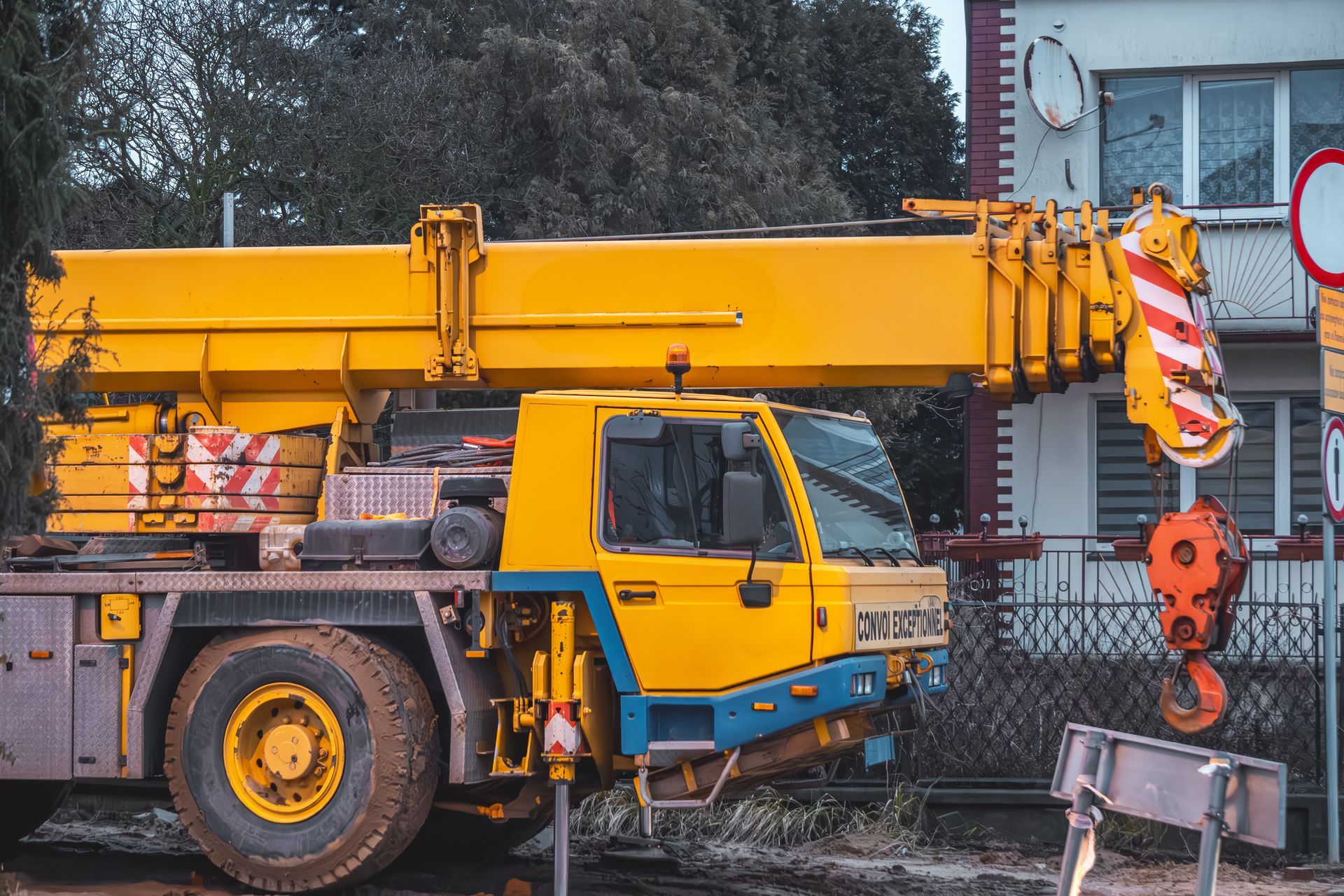 A yellow and blue crane is parked in front of a building.