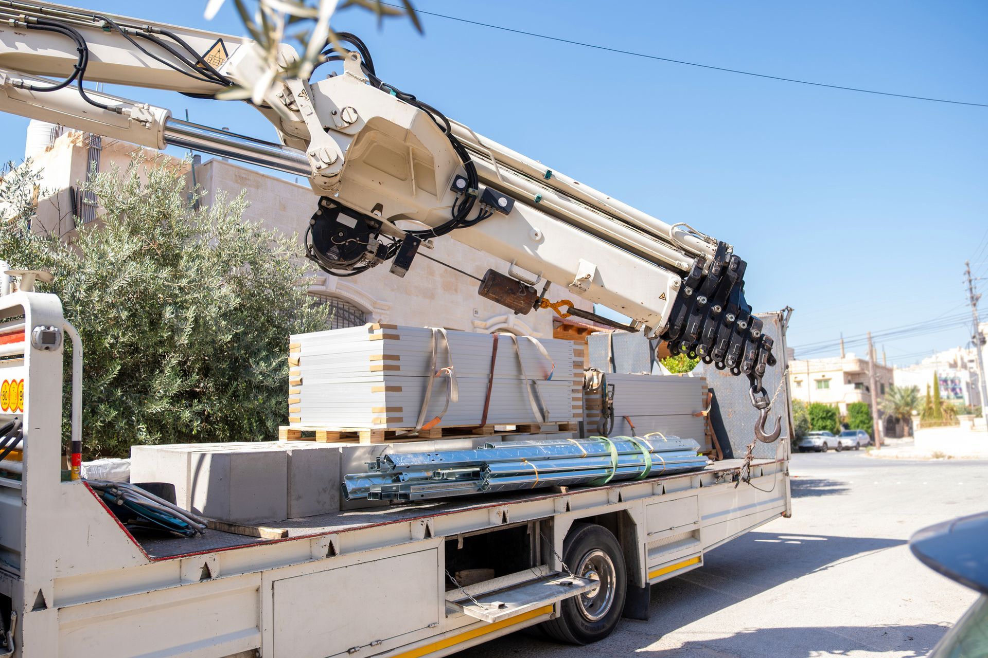 A white truck with a crane on the back is parked on the side of the road.