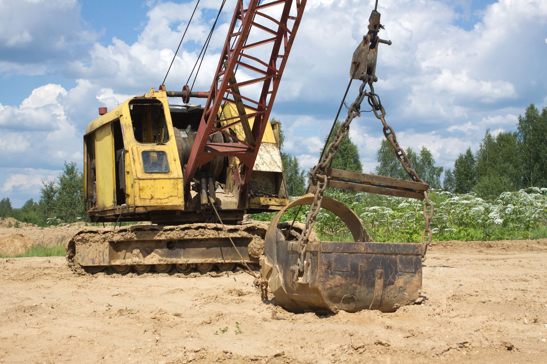 A yellow and red crane with a bucket attached to it