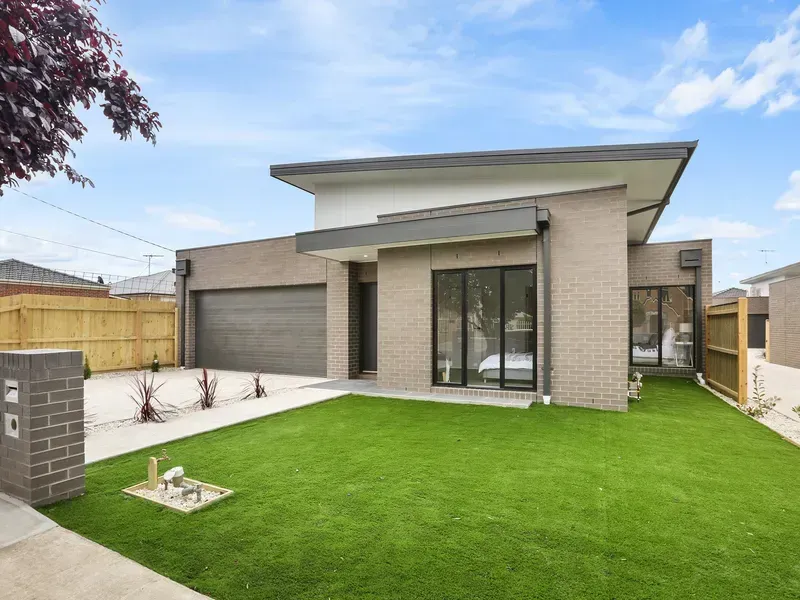 Modern brick house with green lawn, gray garage, and large windows.