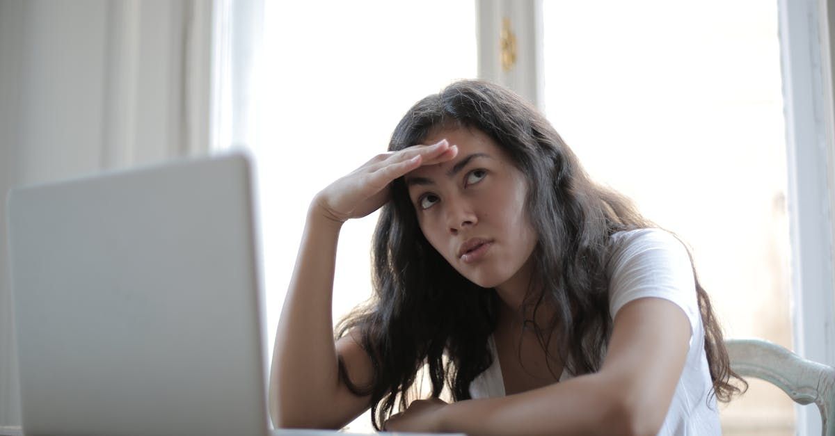 Image of a young woman sitting at her computer thinking