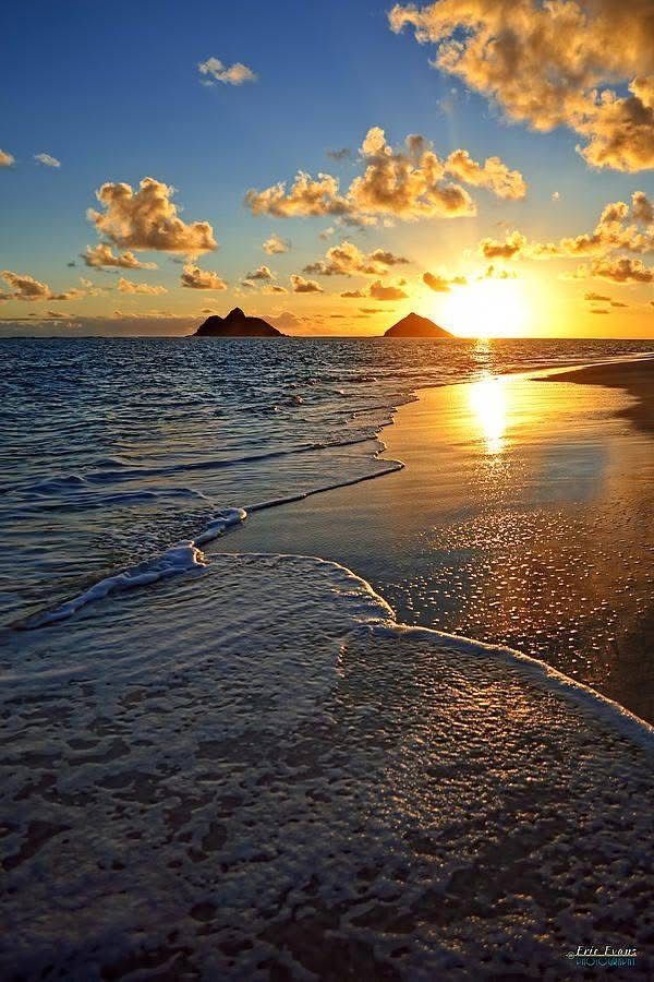 A sunset over the ocean with two small islands in the distance