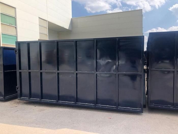 Un gran contenedor de basura negro está estacionado frente a un edificio.