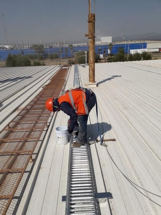 Un hombre está trabajando en un techo blanco con una escalera.