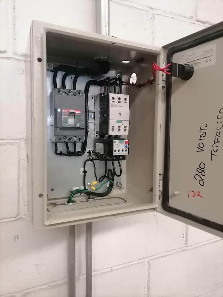 Una caja eléctrica está colgada en una pared de ladrillos blancos.