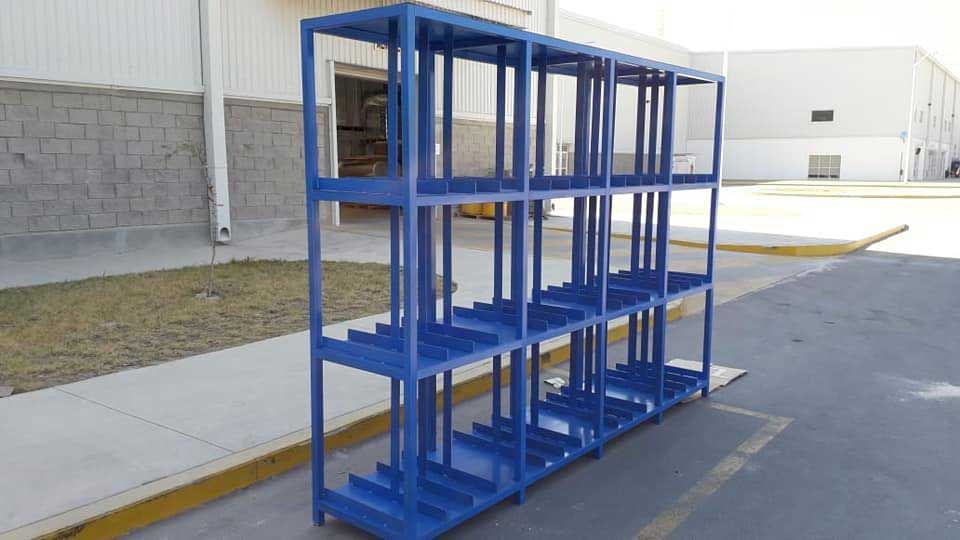Un estante de metal azul se encuentra en un estacionamiento frente a un edificio.