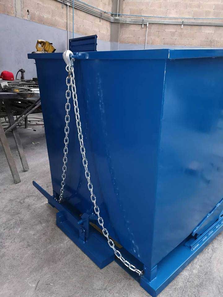 Un contenedor de basura azul con cadenas atadas está tirado en el suelo.