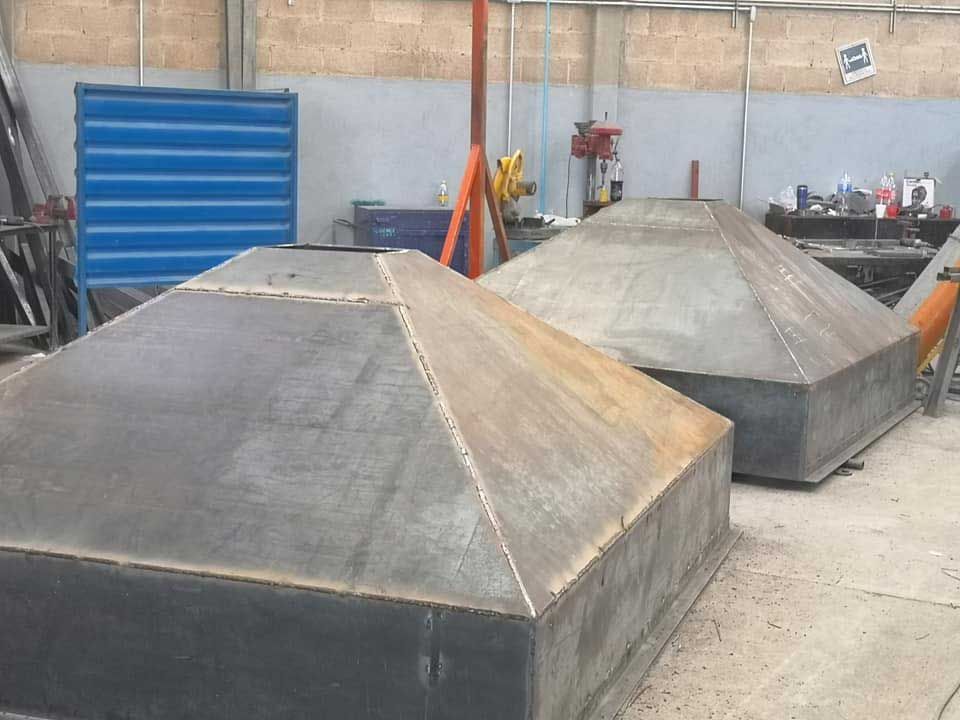 Un grupo de cajas de metal se encuentran en el suelo en una fábrica.