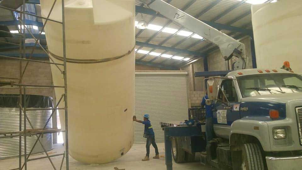 Un hombre está parado junto a un camión en un almacén.