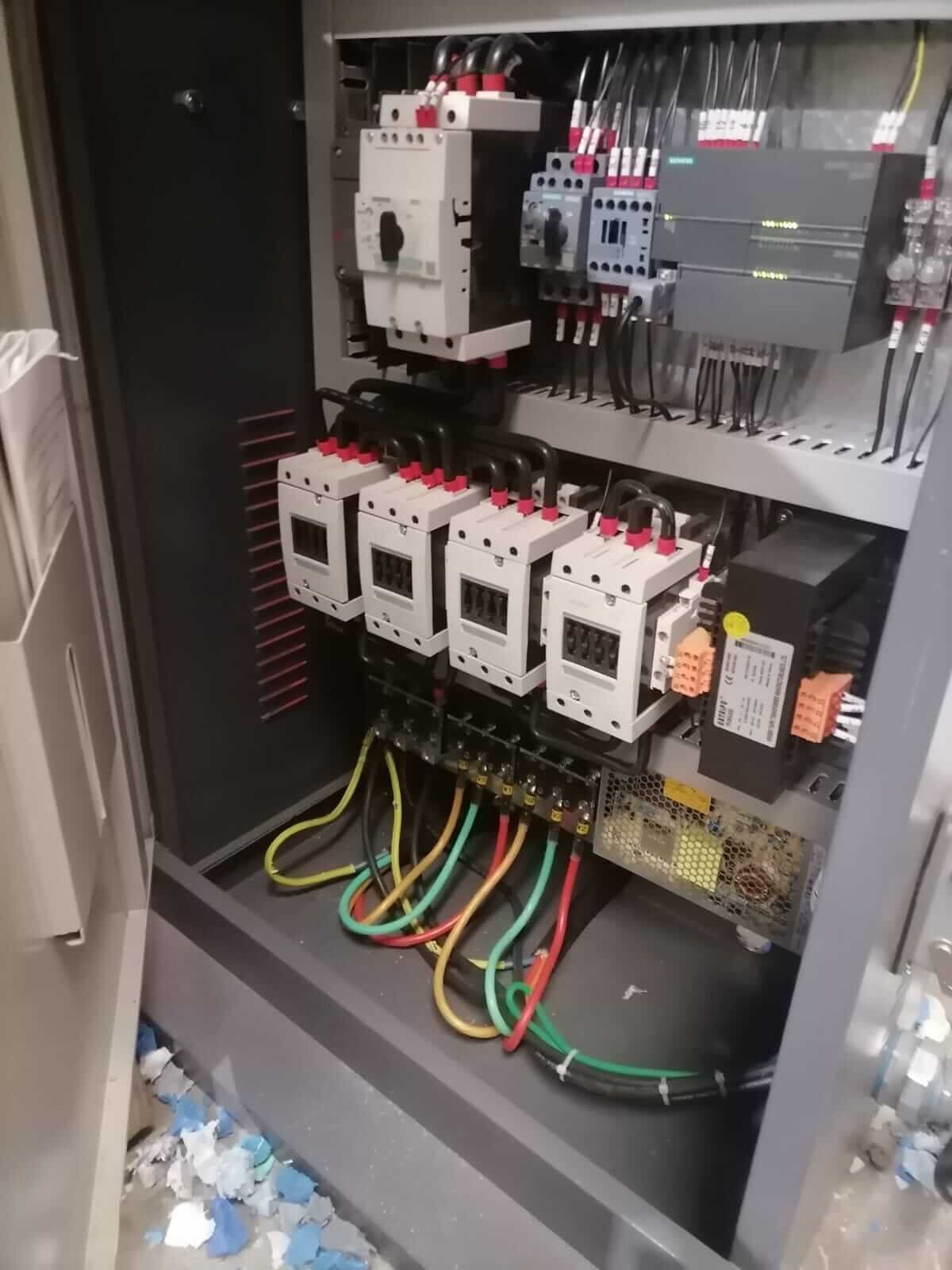 Un primer plano de un panel de control eléctrico con muchos cables saliendo de él.