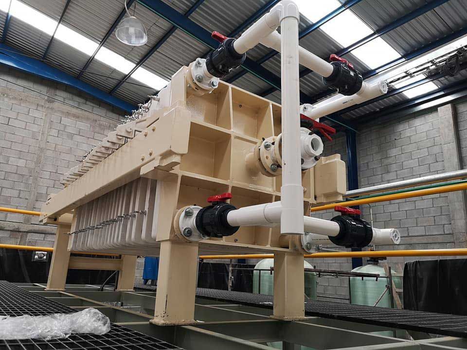 Una máquina grande se encuentra en un almacén con tuberías conectadas a ella.