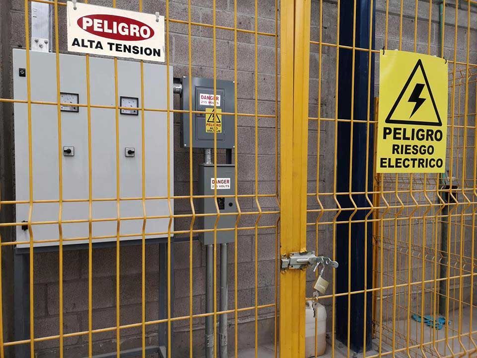 Una valla amarilla con un cartel que dice peligro riesgo electrico