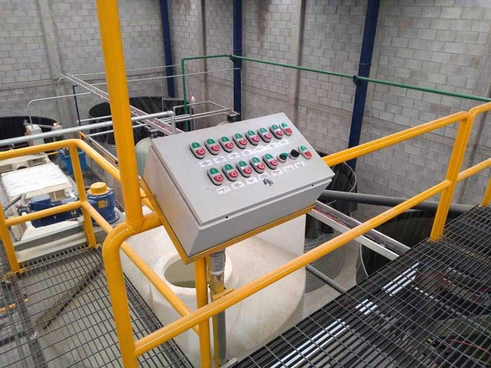Un panel de control está situado encima de una barandilla de metal en una fábrica.