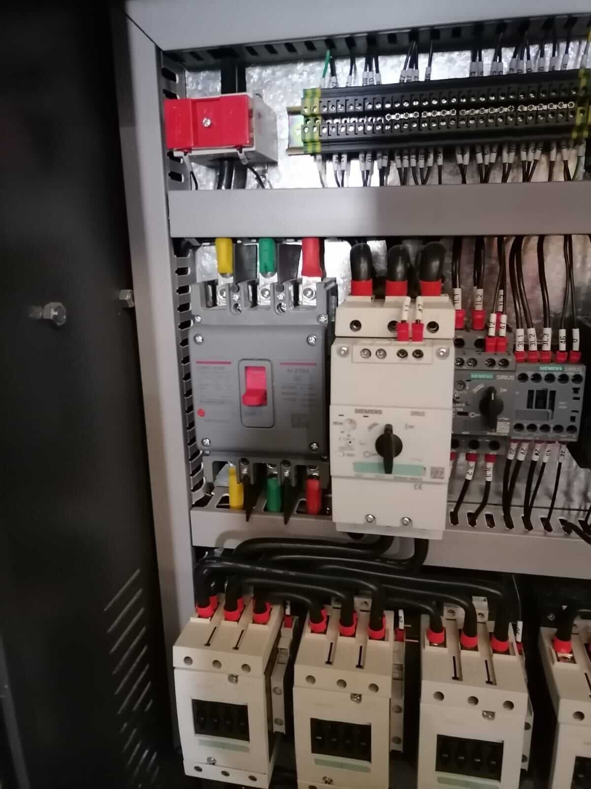 Un primer plano de un panel de control con una gran cantidad de equipos eléctricos en su interior.
