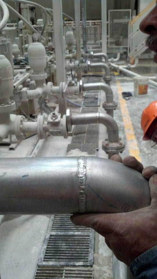 Un hombre sostiene un tubo de acero inoxidable en una fábrica.