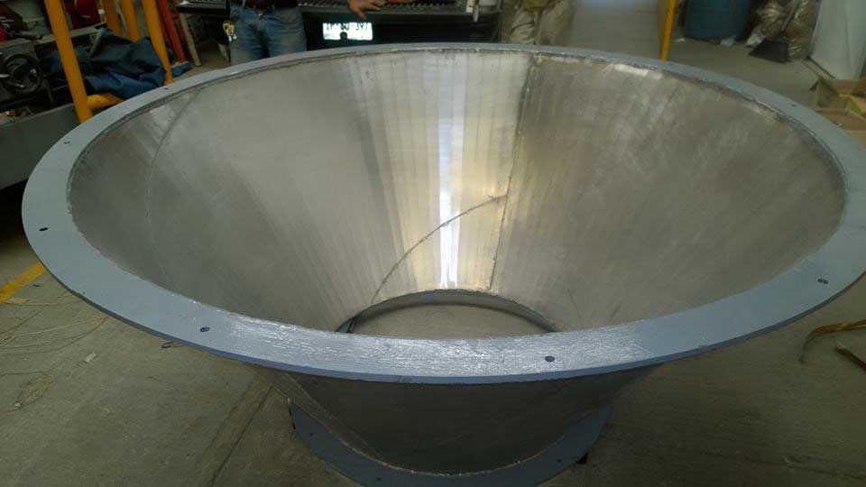 Un gran cono de acero inoxidable se encuentra en el suelo en una fábrica.