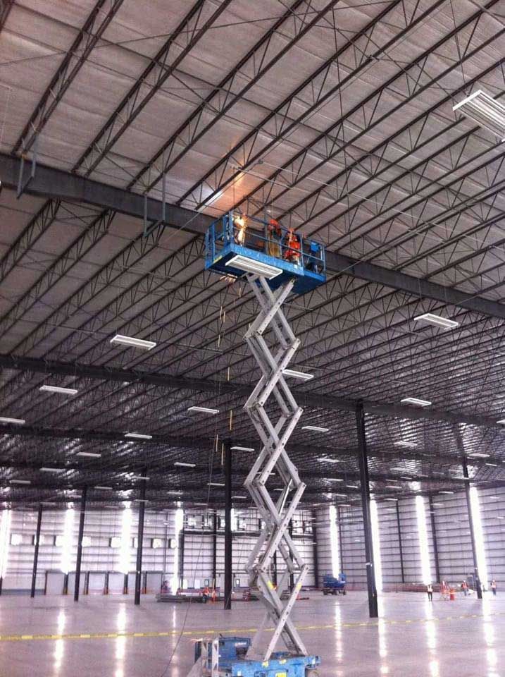 Un hombre está parado en un elevador de tijera en un gran almacén.