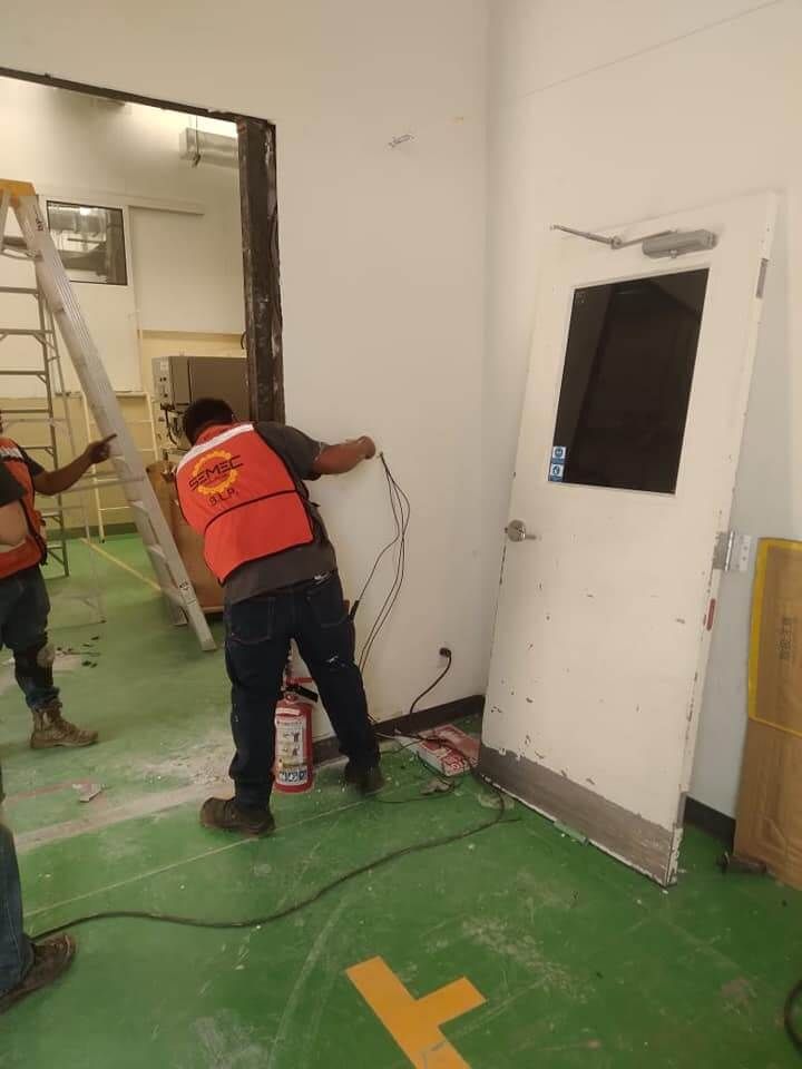 Un hombre con un chaleco naranja está trabajando en una puerta de una habitación.