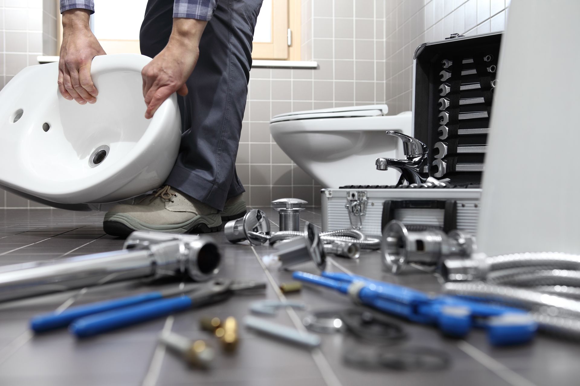 A plumber is installing a sink in a bathroom.