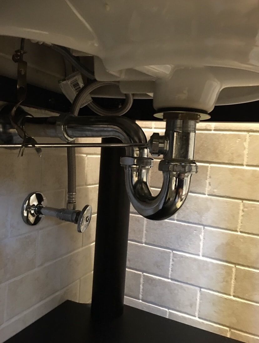 A sink with a plumbing pipe underneath it