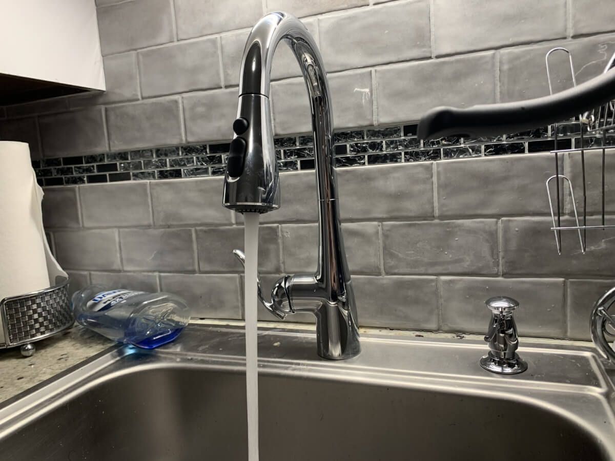 A kitchen sink with water running from the faucet