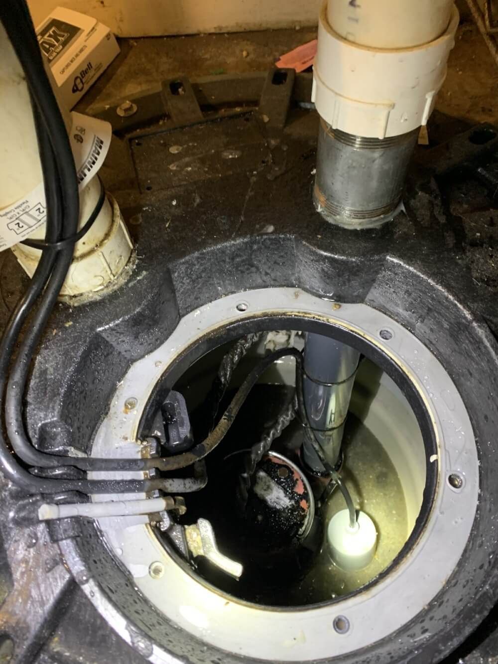 A close up of a sump pump in a basement.