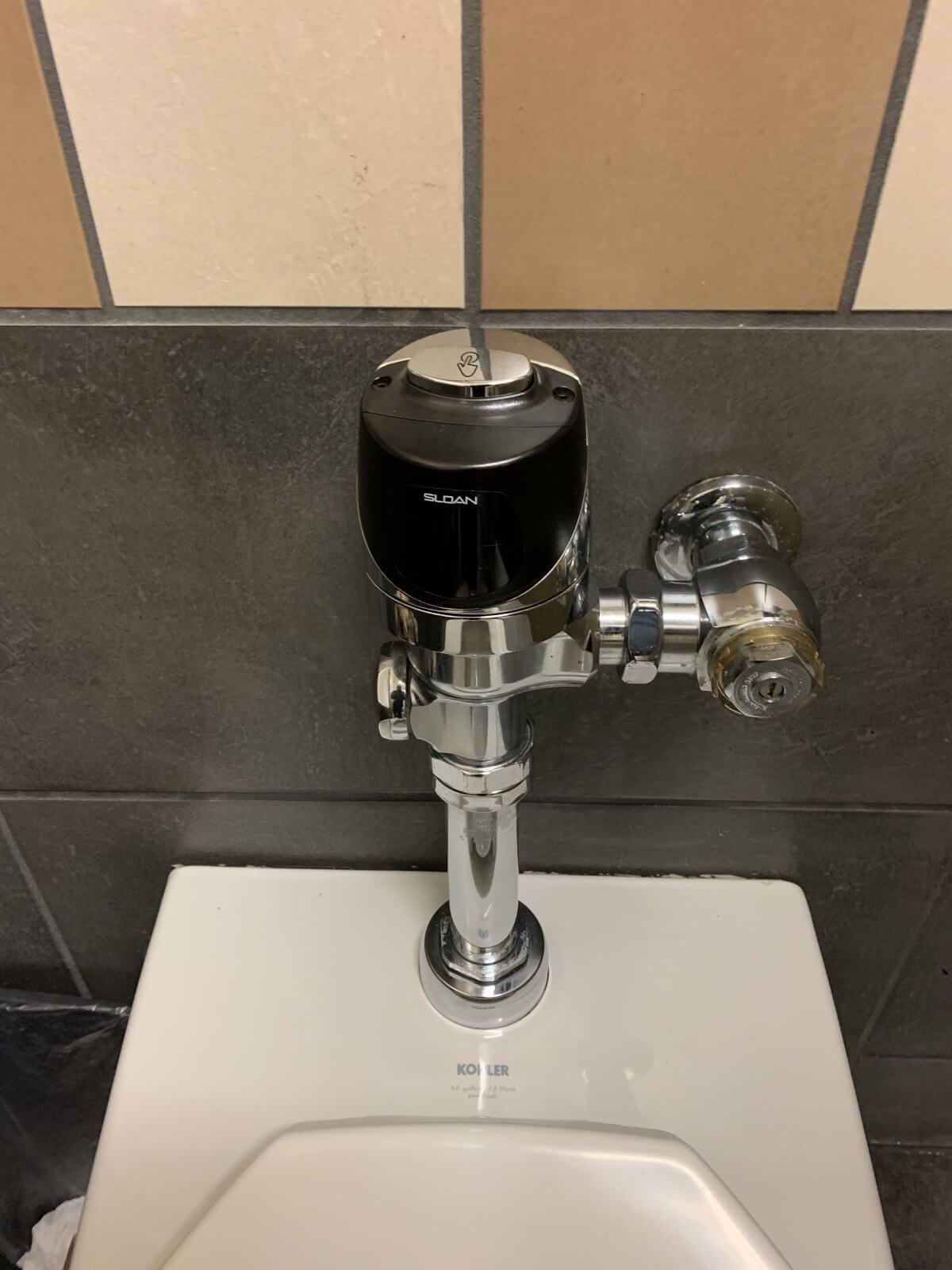 A close up of a toilet flush valve in a bathroom