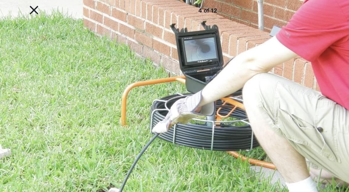 A man is kneeling down in front of a drain camera.