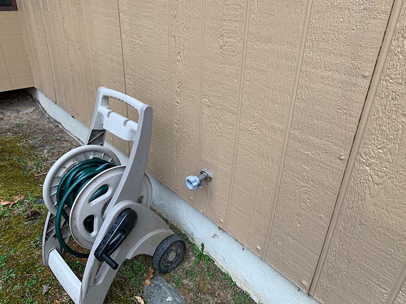 A hose reel is sitting next to a wall.
