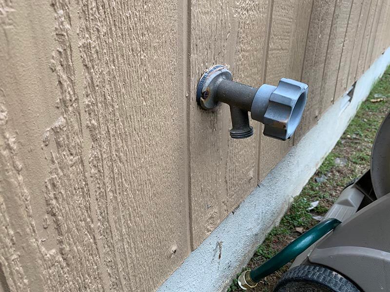A hose is attached to a faucet on the side of a building.