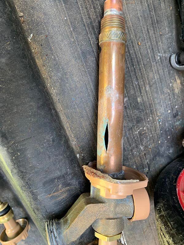 A close up of a copper pipe with a hole in it.