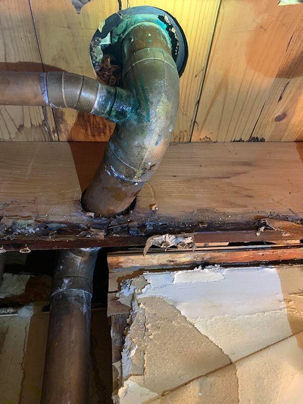 A close up of a copper pipe in a wooden wall.