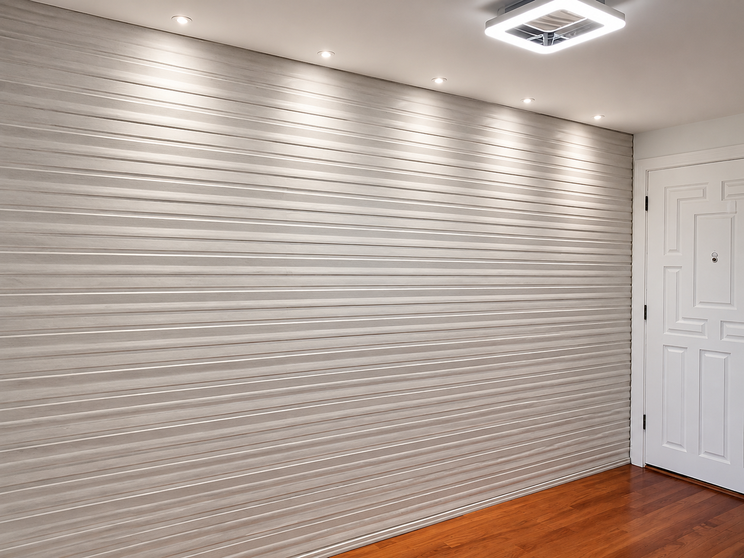 Empty room with textured silver accent wall, hardwood floor, and a white door near the corner.