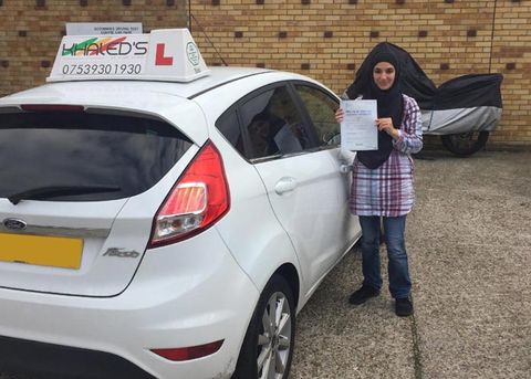 Woman passing driving test and standing next to white car