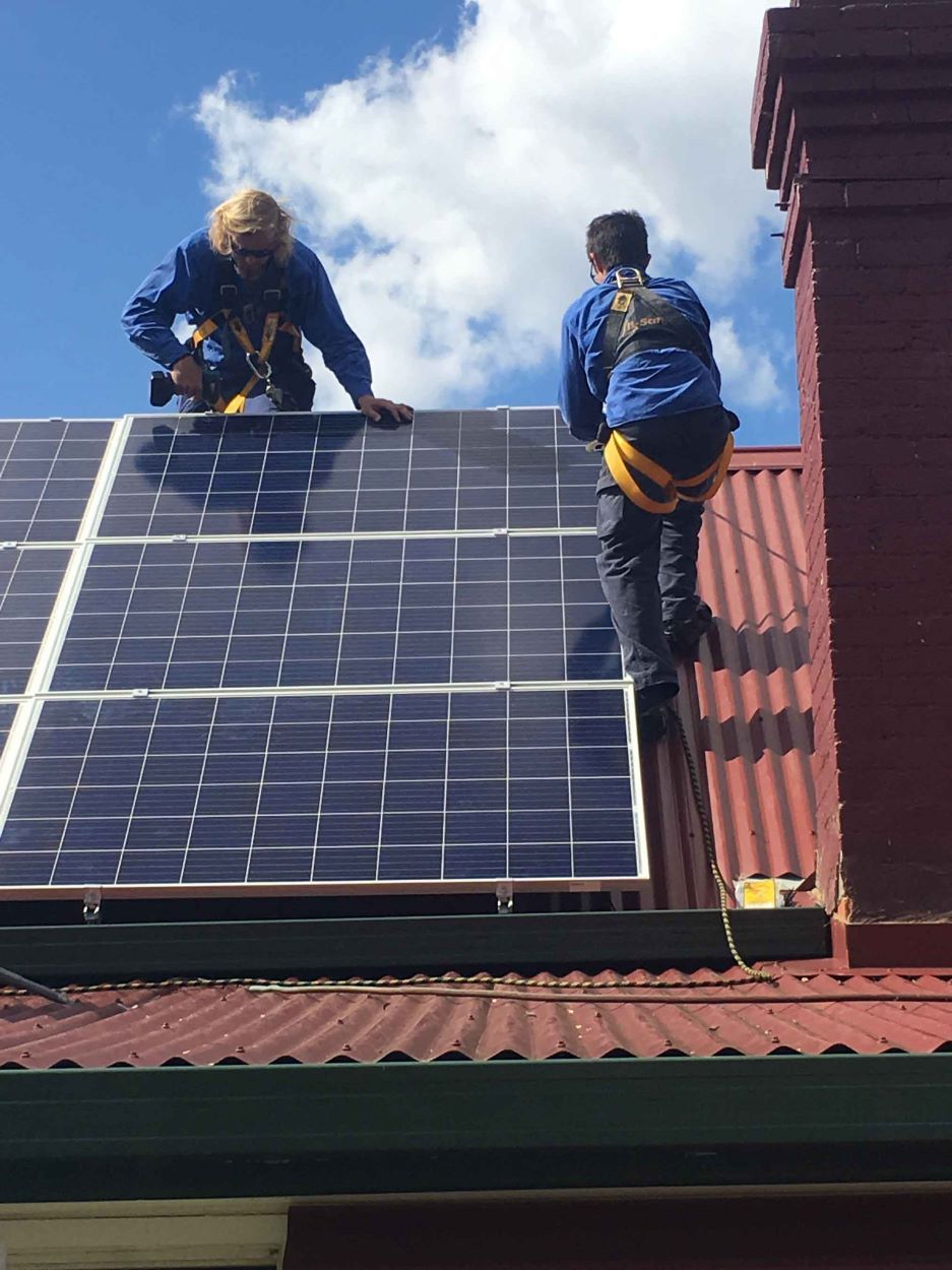 Two Men Are Installing Solar Panels on a Roof — Sapphire City Solar & Electrical In Inverell, NSW
