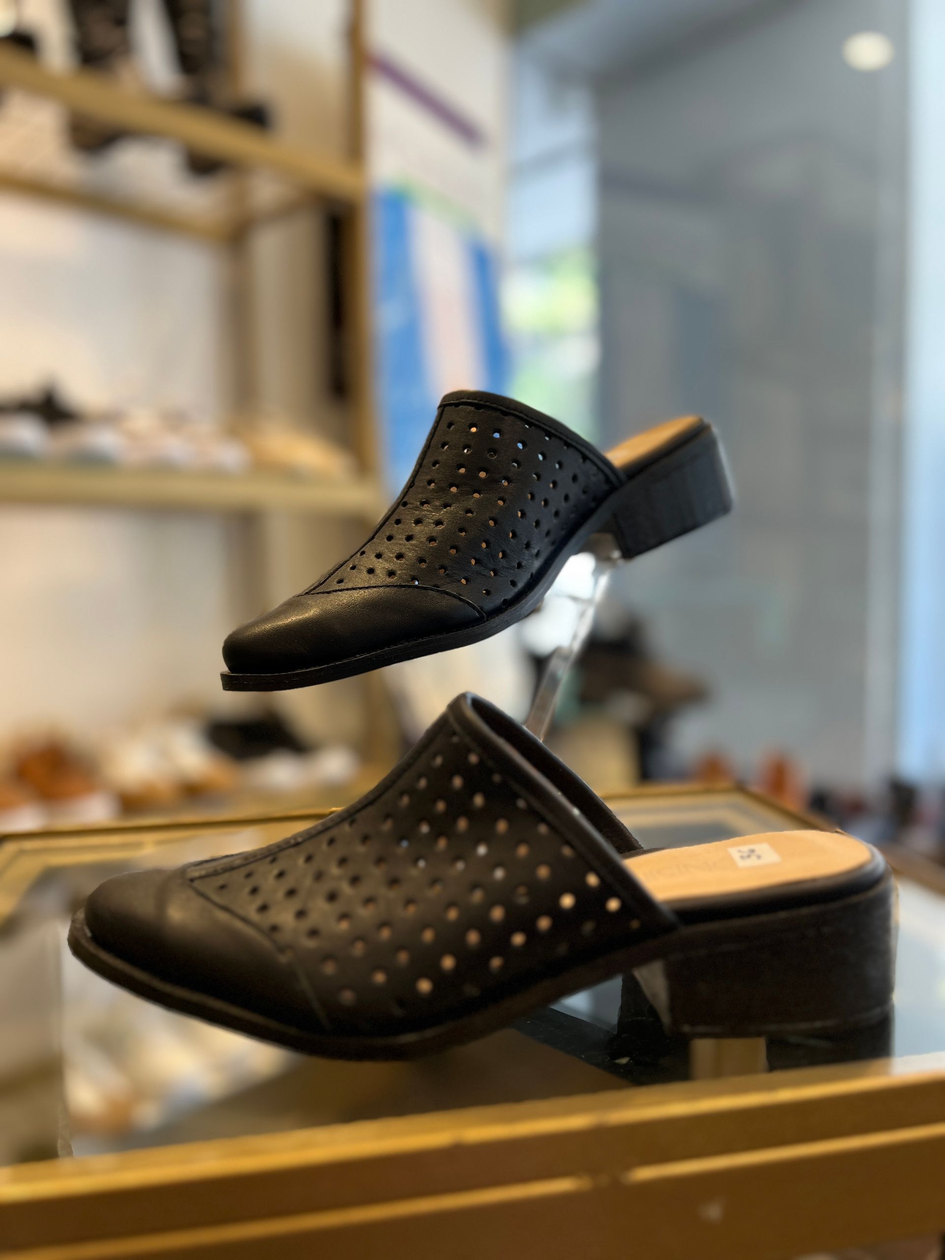 Un par de zapatos negros colocados encima de un estante de vidrio.