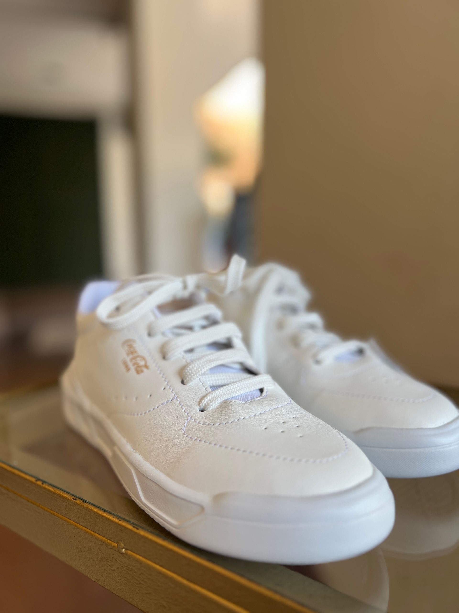 Un par de zapatillas blancas están encima de una mesa de cristal.