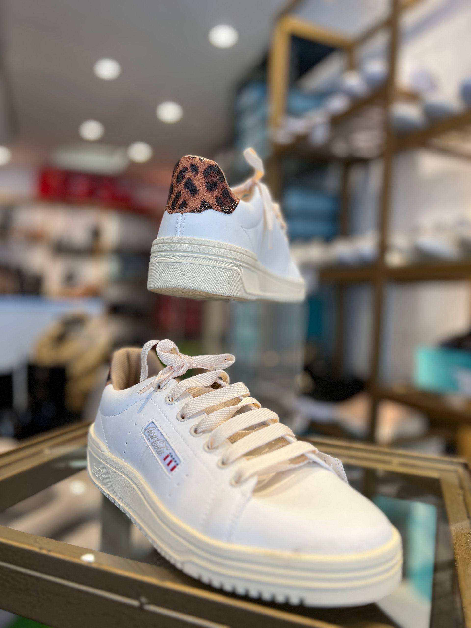 Un par de zapatillas blancas con estampado de leopardo en la parte trasera.