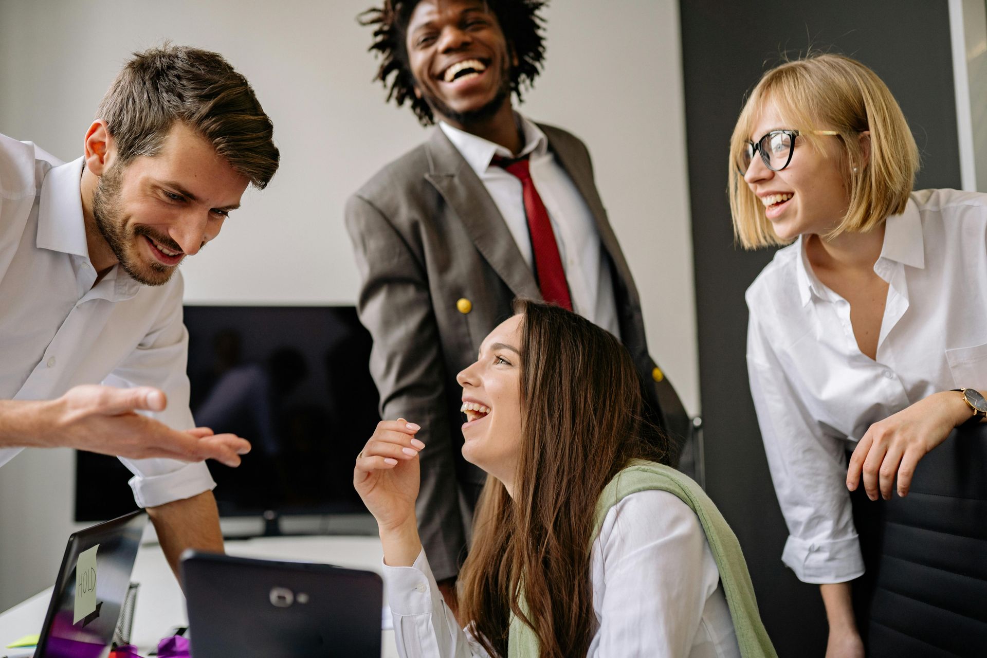 A group of people are standing around a laptop computer.