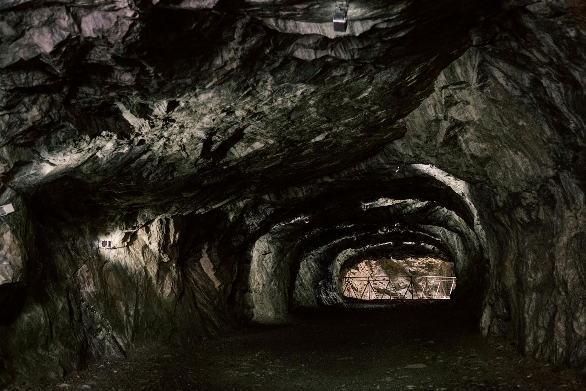 Inside a dark, rocky mine tunnel with a bright exit ahead, symbolising the harsh environments where 