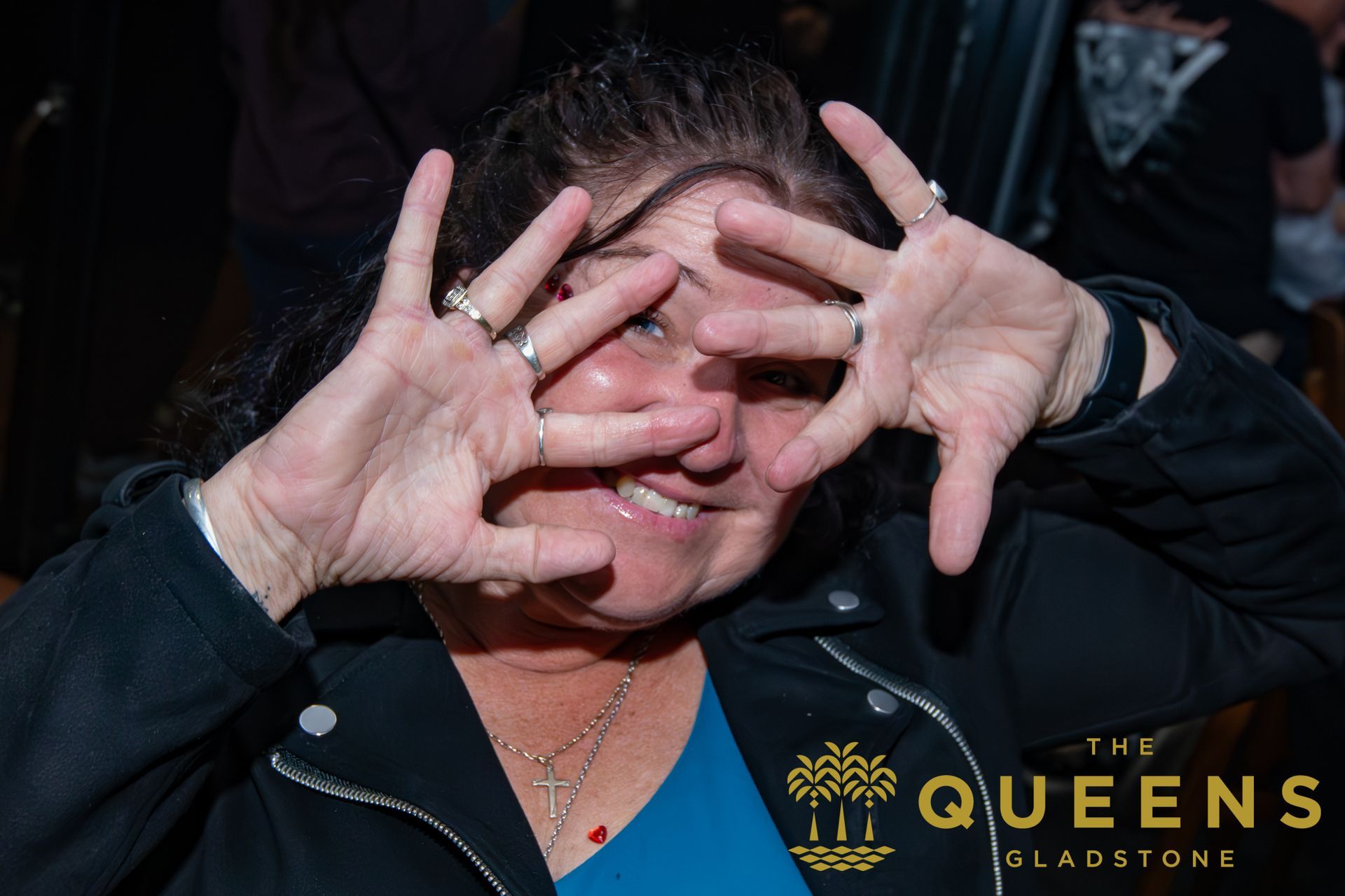 Woman smiling and posing with hands framing her face at a Queens Gladstone event