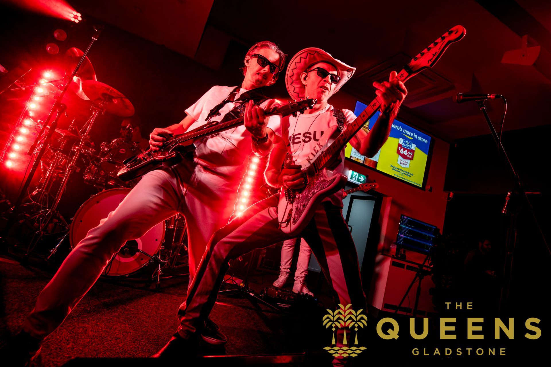 Two musicians performing on red-lit stage at The Queens, Gladstone